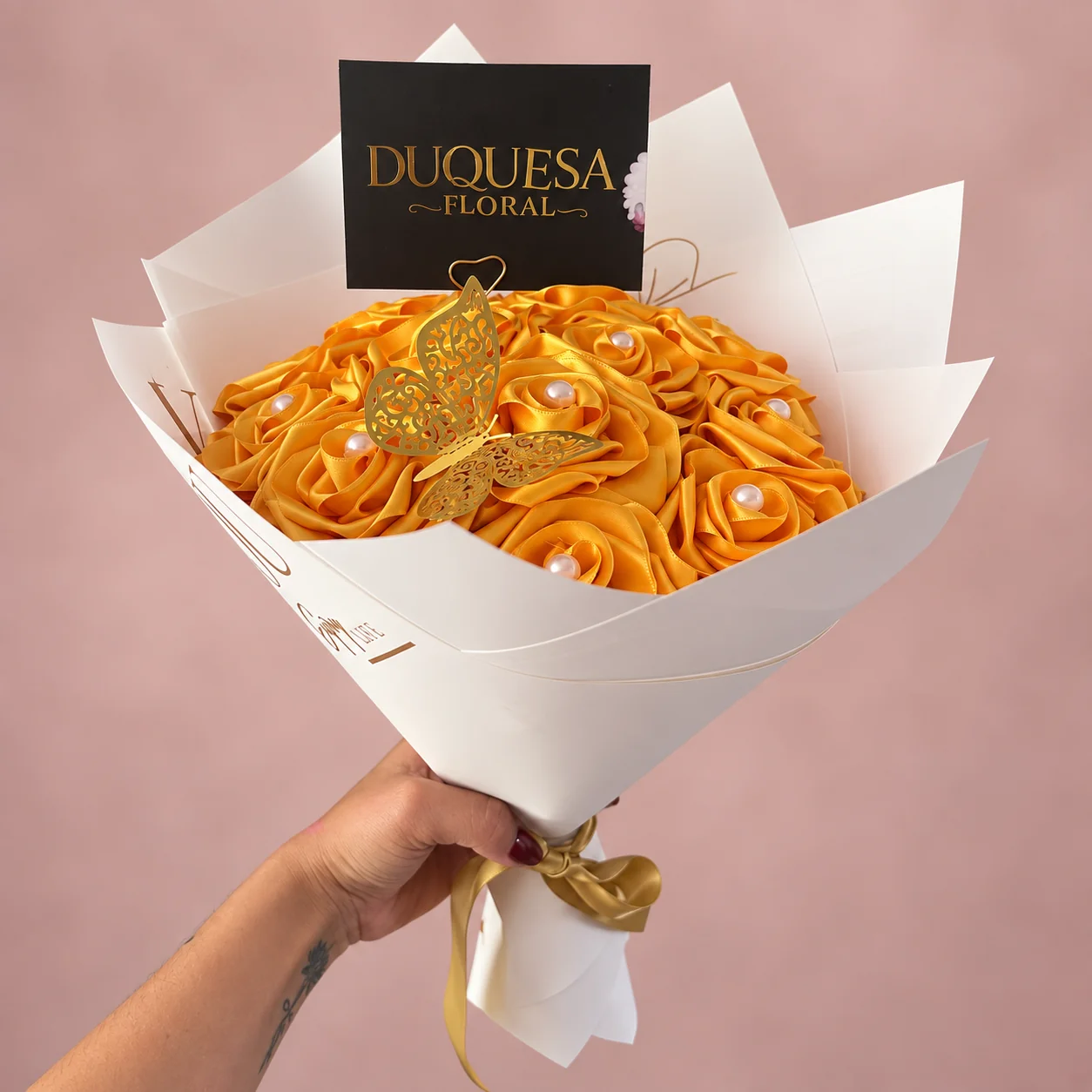 Docena Eterna Dorada - 12 rosas eternas en tono amarillo dorado con perlas y mariposa, en papel blanco con lazo dorado
