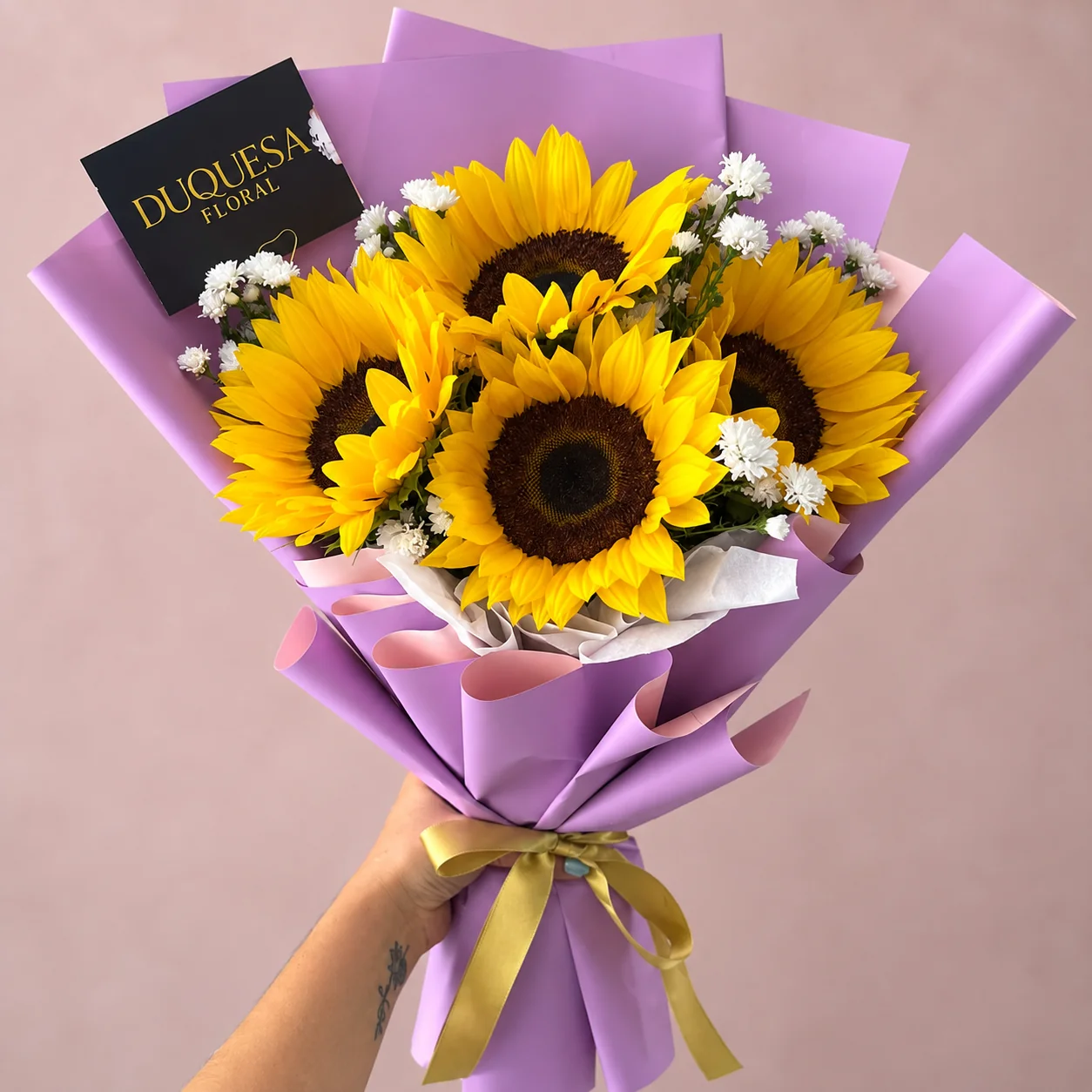 Tres Soles - Ramo de 3 girasoles con flor nube, envuelto en papel lila con lazo dorado